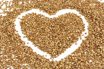 Background (texture) of brown buckwheat with a drawn heart close-up, side view. Template, design.
