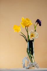 vertical shot, glass vase with flowers on the table, pastel colors