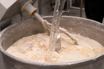 Close-up of the process of pouring water and kneading bread dough in a kneading machine in a...