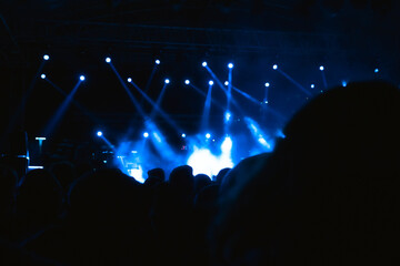 Silhouette of People in the concert area with spotlights on the stage