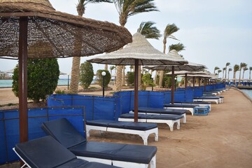 Row of sunbeds and umbrellas, on a beach in Hurghada, Egypt, on a cloudy day.