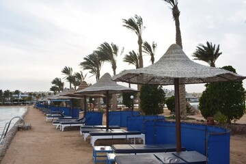 Row of sunbeds and umbrellas, on a beach in Hurghada, Egypt, on a cloudy day.