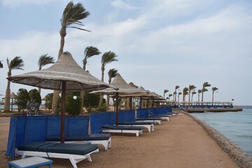Row of sunbeds and umbrellas, on a beach in Hurghada, Egypt, on a cloudy day.