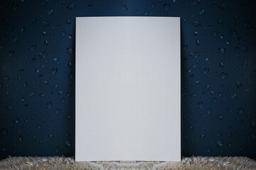 A white sheet of paper stands vertically on a light carpet and an isolated dark background with water drops