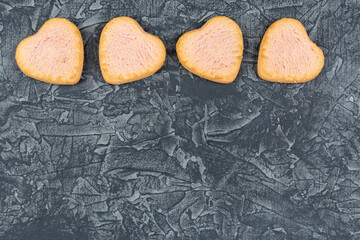 Beautiful sweet raspberry cookies in the shape of a heart on a dark (black) background. Space for the text. The concept of love and celebration and loyalty. Recipe, list of ingredients.