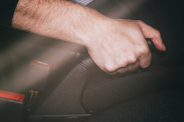 Close-up of a man's hand in a rubber glove pulling the handbrake lever in a car. The driver pulls on the handbrake in the car to activate the parking brake, the importance of the parking brake.