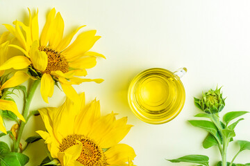 Glass bowl full of sunflower oil and sunflower flowers on a white background.Top view. Space for...