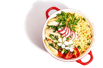 Asian noodles with chicken, vegetables, and herbs are isolated on a white background