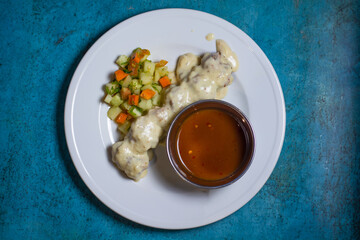 Chicken Malai Tikka boti with salad chilli sauce and onion rings served in a plate top view of indian bbq fast food