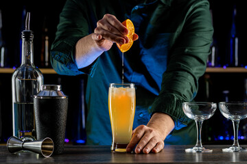 Bartender's hands serving cocktails on bar counter in a restaurant, pub. Mixed drinks. Alcoholic cooler beverage at nightclub on dark background