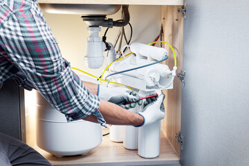 Technician installing or repairing system of water filtration. Plumber hand in gloves replace water...