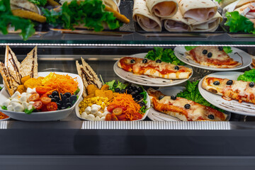 Glazed showcase inside a cafe with fresh Italian dishes and herbs in Milan, national Italian cuisine for fast food, close-up