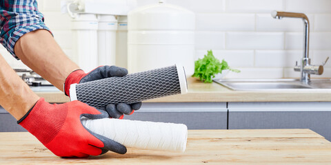 Hands holding a filter cartridge of domestic drink water treatment systems at kitchen background....