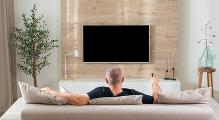 man in modern living room watching tv back view