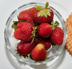 ripe strawberries with cookies on a white dish