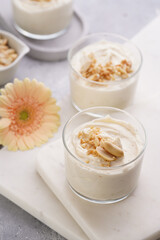 Creamy dairy yoghurt dessert with mascarpone, cream cheese and peanut butter in glasses on marble tray