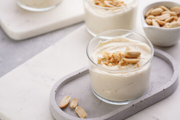Creamy dairy yoghurt dessert with mascarpone, cream cheese and peanut butter in glasses on concrete tray