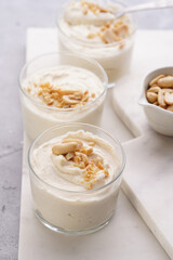 Creamy dairy yoghurt dessert with mascarpone, cream cheese and peanut butter in glasses on marble tray