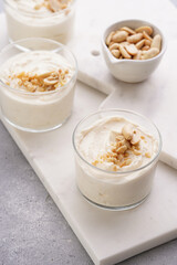 Creamy dairy yoghurt dessert with mascarpone, cream cheese and peanut butter in glasses on marble tray