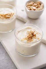 Creamy dairy yoghurt dessert with mascarpone, cream cheese and peanut butter in glasses on marble tray