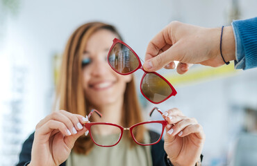 A young Latina in an optician's shop tries on glasses with a magnet accessory.