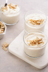 Creamy dairy yoghurt dessert with mascarpone, cream cheese and peanut butter in glasses on marble tray