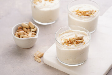Creamy dairy yoghurt dessert with mascarpone, cream cheese and peanut butter in glasses on marble tray