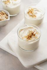 Creamy dairy yoghurt dessert with mascarpone, cream cheese and peanut butter in glasses on marble tray