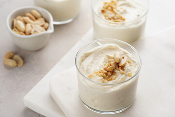 Creamy dairy yoghurt dessert with mascarpone, cream cheese and peanut butter in glasses on marble tray