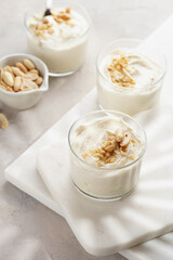Creamy dairy yoghurt dessert with mascarpone, cream cheese and peanut butter in glasses on marble tray
