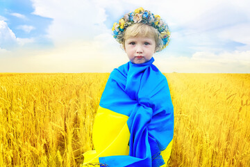 little sad Ukrainian girl wrapped in Ukrainian flag. child with a traditional wreath on head....