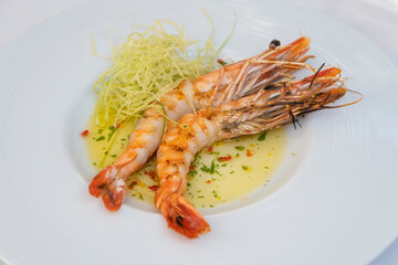 Plate of grilled prawns with sauce and vegetable sides. Luxury restaurant plate presentation