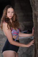 Woman posing in a cave with a criss cross swimsuit