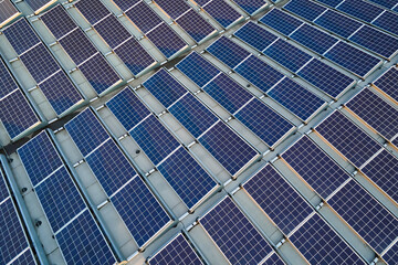 Aerial view of blue photovoltaic solar panels mounted on industrial building roof for producing green ecological electricity. Production of sustainable energy concept