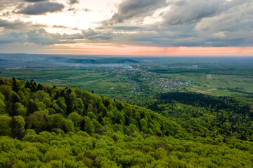 Aerial view of dark mountain hills covered with green mixed pine and lush forest in evening