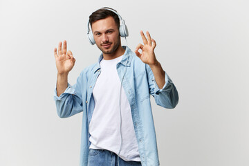 Cheerful smiling tanned handsome man in casual basic t-shirt headphones show Okay gesture both hands posing isolated on over white studio background. Copy space Banner Mockup. Cool playlist concept