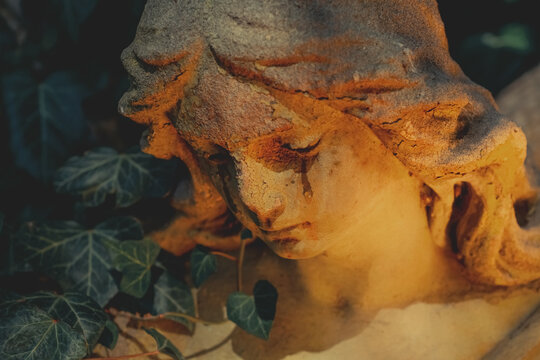 Retro styled image of beautiful sensual angel crying as symbol of pain, death and fear. Fragment of an ancient statue.