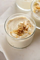 Creamy dairy yoghurt dessert with mascarpone, cream cheese and peanut butter in glasses on marble...