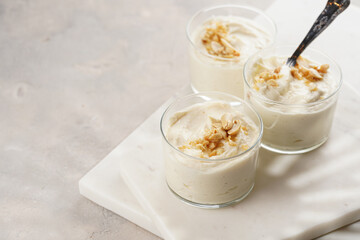 Creamy dairy yoghurt dessert with mascarpone, cream cheese and peanut butter in glasses on marble tray with a tea spoon