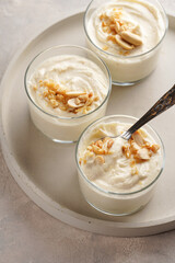 Creamy dairy yoghurt dessert with mascarpone, cream cheese and peanut butter in glasses on concrete tray with a tea spoon