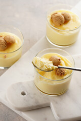 Creamy french vanilla pudding in glass decorated with italian biscuits amaretti on marble board on grey neutral background