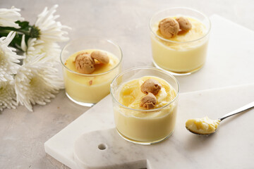 Creamy french vanilla pudding in glass decorated with italian biscuits amaretti on marble board on...