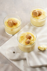 Creamy french vanilla pudding in glass decorated with italian biscuits amaretti on marble board on grey neutral background