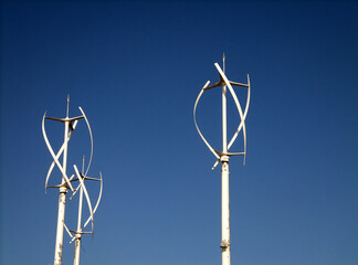 a group of small vertical wind turbines against a blue sky