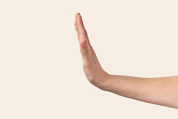 Female hand stop gesture on beige. - obrazy, fototapety, plakaty