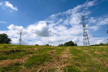 Communications tower on field with cloudy sky
