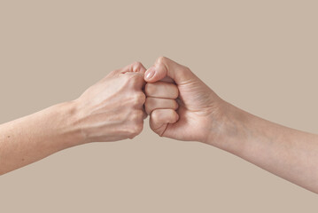 Two hands of man and woman fist bump on beige.