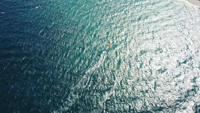 Aerial drone view of windsurfer enjoying on blue sea ocean waves.	
