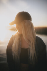 Poważna dziewczyna na tle zachodzącego słońca nad jeziorem
