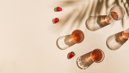 Summer refreshment concept. Decorative glasses with beverage and strawberries lying around on yellow background